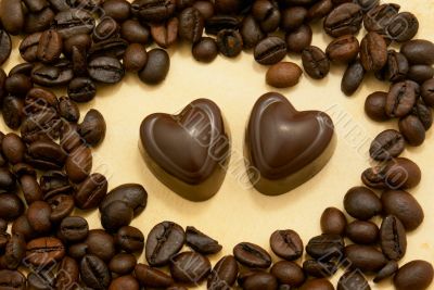 Two heart shaped chocolate candies and coffee beans