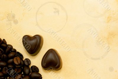 Two heart shaped chocolate candies and coffee beans