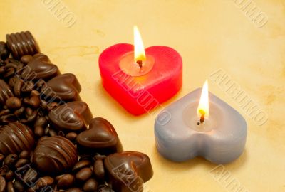 Two burning heart shaped candles and candies