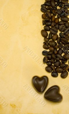 Two heart shaped chocolate candies and coffee beans