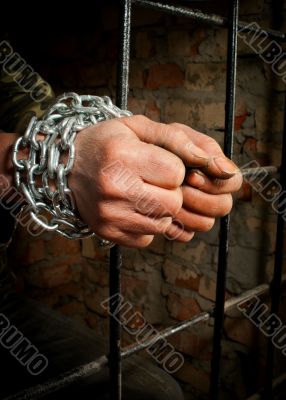 Man with hands tied up with chains