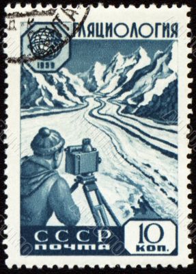 Researcher with device in mountain on post stamp