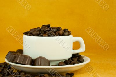 Cup full with coffee beans and chocolate candies