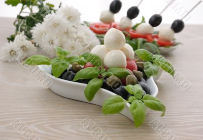 Appetizer of mozzarella, cherry tomatoes and olives and basil