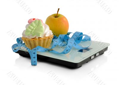 Cake and apple on scales measuring tape wrapped