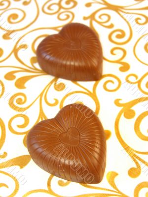 Mouthwatering chocolates in a heart-shaped on a colored background 