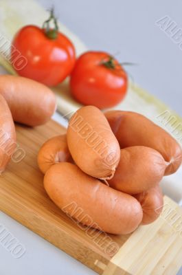 Delicious sausages on a cutting board and ripe tomatoes 