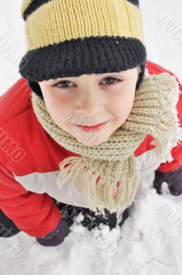 Portrait of a cute boy sitting in the snow 