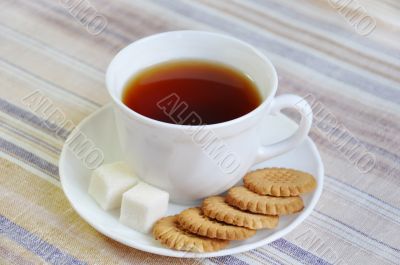 A cup of tea with biscuits and slices of sugar