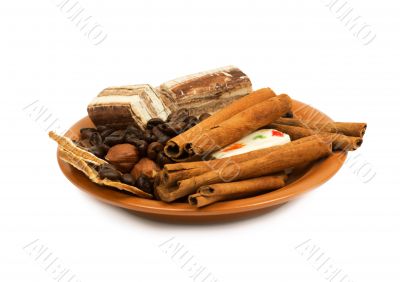 Sweets, cinnamon, nuts and coffee beans on a saucer.