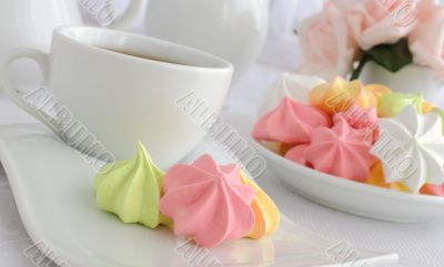 Meringue cookies on a plate with a cup of coffee