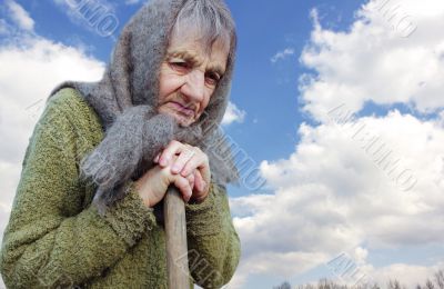 The grandmother is thinking leaning on a stick