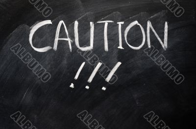 Caution written on blackboard