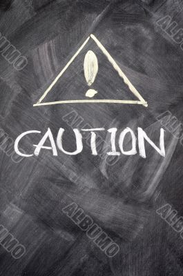 Caution written on blackboard