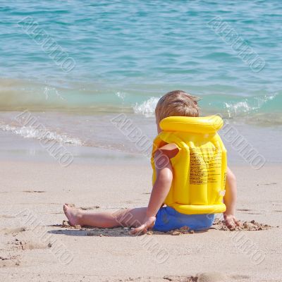 Liitle boy on the beach in lifejacket
