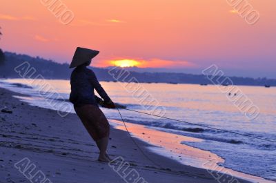 Silhouette of a fisherman on beach at sunrise
