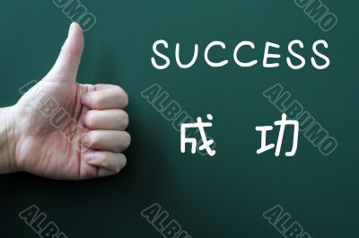 Success written on a blackboard with a thumb up