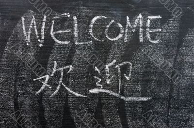Welcome - word written on a blackboard with a Chinese version