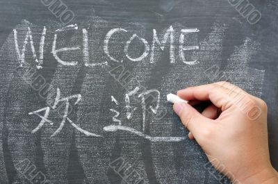 Welcome - word written on a blackboard with a Chinese version