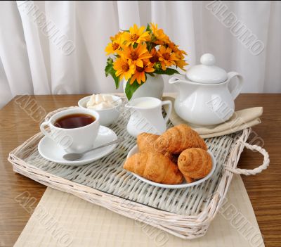 croissants with tea and milk on a tray