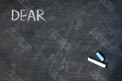 Smudged blackboard background with chalk and the word dear