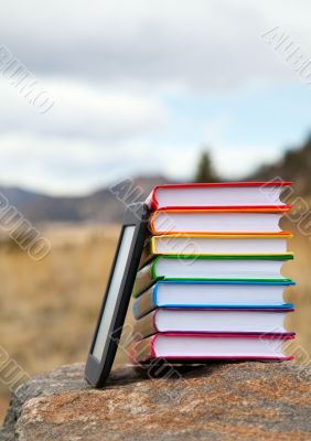 Stack of printed books with electronic book reader