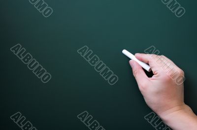 Blackboard background with a hand holding chalk writing.