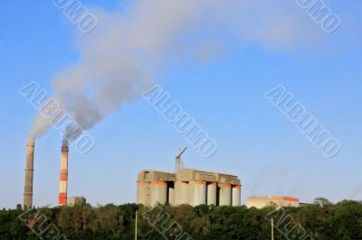 Smoke stacks of cement factory. Summertime landscape