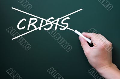Crossing out crisis on a green chalkboard