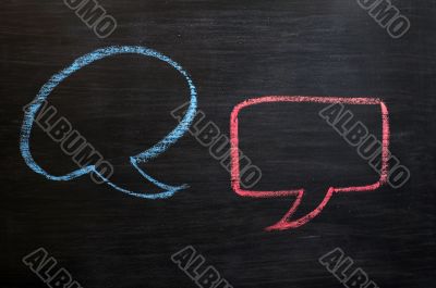 Chalk drawing of blank speech bubbles on a blackboard background