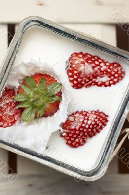 Strawberry falling and splashing into milk