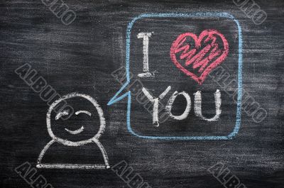Speech bubble with a cartoon figure, saying I love you drawn on a blackboard background