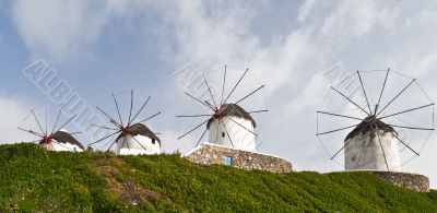 Windmills behind green grass mountainside