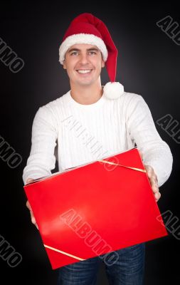 Smiling man in Santa hat gives a red box in the studio