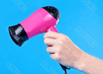 Pink hair dryer in the female hand