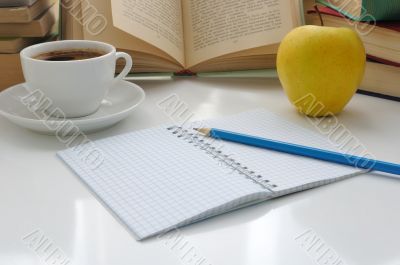 Notebook with a pencil on a table with a cup of coffee and an ap