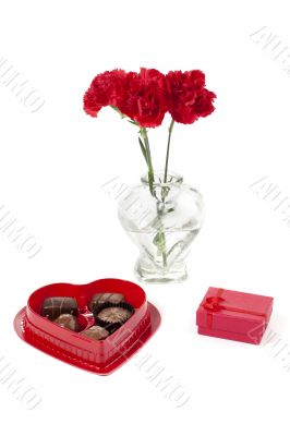 a red flower with chocolates and jewelry 