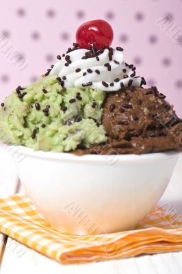 a bowl with chocolate and mint ice cream and cherry on the top