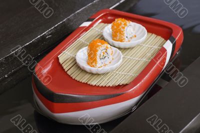 two shushi in white plate on toy boat
