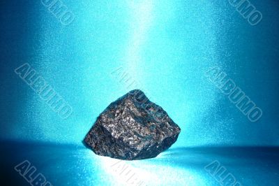 Dark gray shiny stone on a blue background.