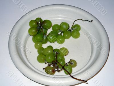 Green overripe grapes in the plate