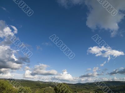 blue sky with grey clouds with tuscan landscape