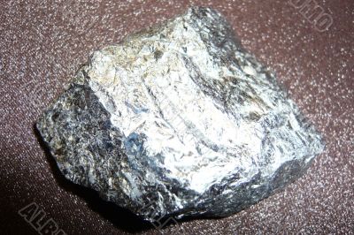 Silvery shiny stone on a dark brown background.