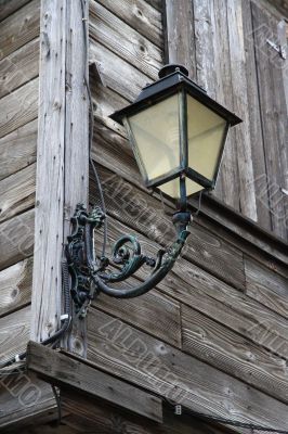 Street lantern on the wall of wooden house