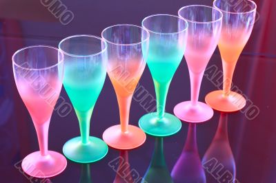 Colored glasses are on the table made â€‹â€‹of black glass.