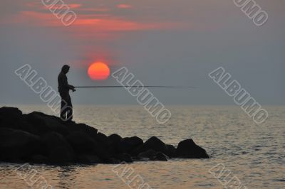 The fisherman at sunset is waiting for fish to bite