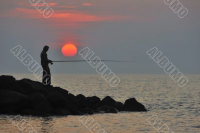 The fisherman at sunset is waiting for fish to bite