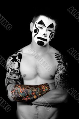 pumped up young man with tattoos and painted face