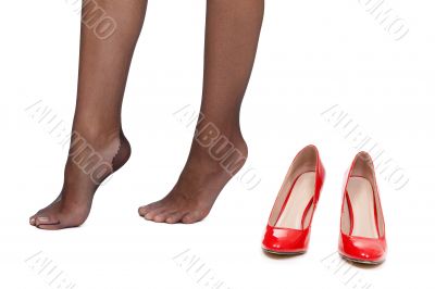 Tired female legs on a white background next to the red shoes