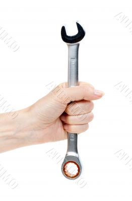 Woman`s hand holding a chrome wrench.